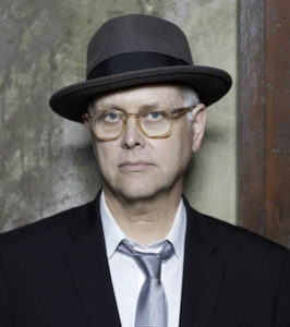 Photo of Eddie Muller wearins suit, glasses, and hat, very noir looking